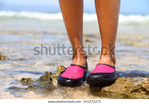 Water shoes /
swimming shoe in Pink neoprene on rocks in water on beach. Closeup
detail of the feet of a woman wearing neoprene water shoes standing
on rocks at the edge of the
ocean.