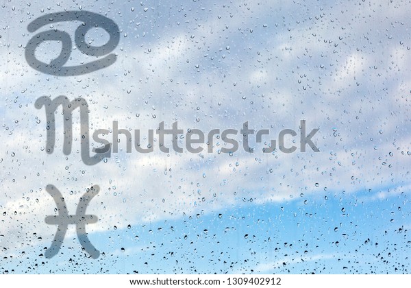Water signs of the\
zodiac. Three astrological symbols - cancer, scorpion and pisces.\
Drawing a finger on the misted glass. Glass window with raindrops\
against the blue sky.