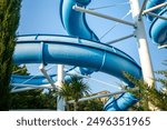 Water Slide, Amusement Park, Summer - A blue water slide twists and turns in an amusement park on a sunny day.