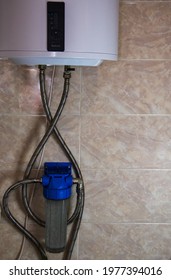 A Water Softener Is Attached To The Wall, Connected To A Boiler, An Electric Water Heater. Close-up Of A Compact Water Softening And Filtration System. Universal Water Softening System For Home