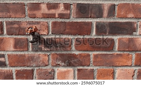 a water spigot on the exterior red brick wall of a building