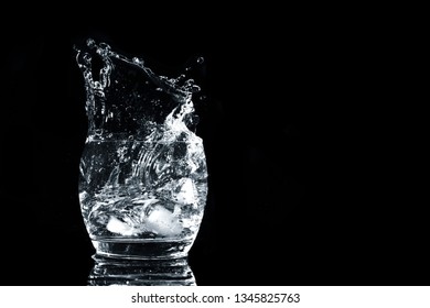 Water Splash Glass Cup Isolated On Black Background. Refreshing Drink Of Water Splashes In Air. High Speed Action. Ice In Refreshment. Refreshing Aqua.