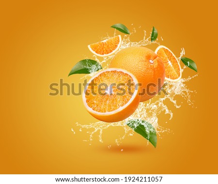 Water splash on fresh orange with leaves isolated on orange background. 
