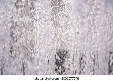 Water Splashes From Fountain On Dark Background. Natural Texture Of Only Water Of Fountain. High Waves Effect In Hot Summer With Copy Space. Water Sprays In Sunny Day Close-up.