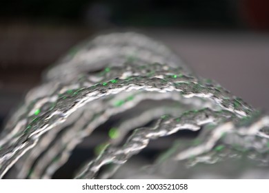 Water Splashes From Fountain On Dark Background. Natural Texture Of Only Water Of Fountain. High Waves Effect In Hot Summer With Copy Space. Water Sprays In Sunny Day Close-up.