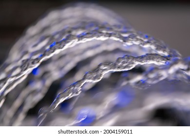 Water Splashes From Fountain On Dark Background. Natural Texture Of Only Water Of Fountain. High Waves Effect In Hot Summer With Copy Space. Water Sprays In Sunny Day Close-up.