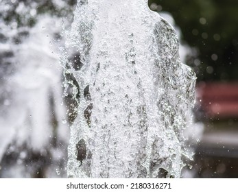 Water Splashes From Fountain On Dark Background. Natural Texture Of Only Water Of Fountain. High Waves Effect In Hot Summer With Copy Space. Water Sprays In Sunny Day Close-up.