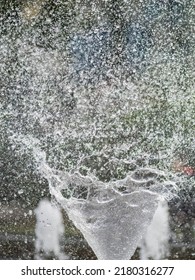 Water Splashes From Fountain On Dark Background. Natural Texture Of Only Water Of Fountain. High Waves Effect In Hot Summer With Copy Space. Water Sprays In Sunny Day Close-up.