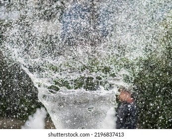 Water Splashes From Fountain On Dark Background. Natural Texture Of Only Water Of Fountain. High Waves Effect In Hot Summer With Copy Space. Water Sprays In Sunny Day Close-up.