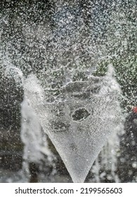 Water Splashes From Fountain On Dark Background. Natural Texture Of Only Water Of Fountain. High Waves Effect In Hot Summer With Copy Space. Water Sprays In Sunny Day Close-up.