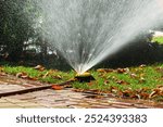 Water splashing from an automatic sprinkler lawn irrigation system on a sunny autumn day