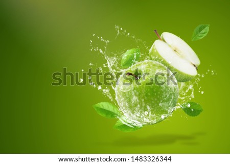Water splashing on Fresh green apple on Green background.