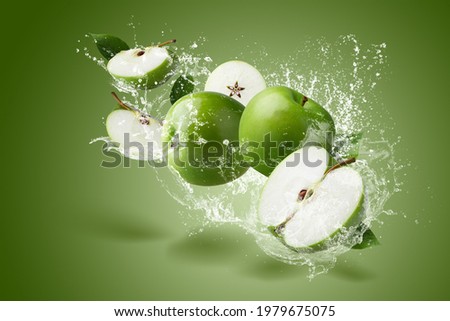 Water Splashing on Green apple  and cut slice with seed on green background.