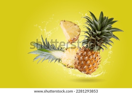 Water Splashing on Split Pineapple Fruit isolated on a yellow background.