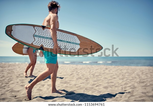 water sports. Healthy Active Lifestyle. Surfing.\
Summer Vacation. Extreme Sport. Young surfer man walking with board\
on the sandy beach. \
