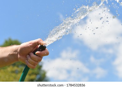 Water Sprays From A Garden Hose. Close Up Of Hand. 