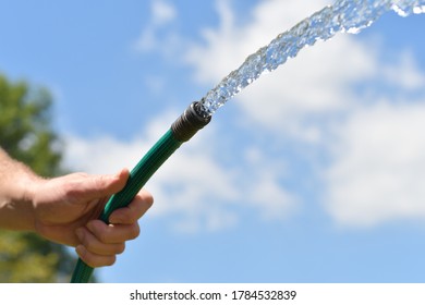 Water Sprays From A Garden Hose. Close Up Of Hand. 