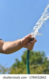 Water Sprays From A Garden Hose. Close Up Of Hand. 