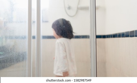 Water Stain On The Glass Shower Door In The Bathroom, Selective Focus With Blurry Asian Toddler As A Background, One Of The Dirty Area In The Household, House Cleaning Management, Household Hygiene.