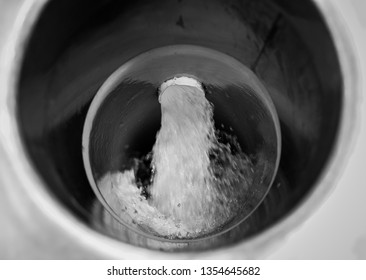 Water stream flows into a pipe for fish at a fish hatchery, viewed close-up from inside