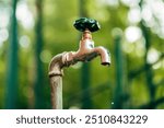 Water supply, outdoor garden faucet with green handle and water dripping, selective focus