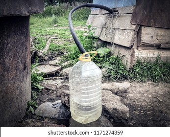 Water Supply Shortage And Climate Change Threats: Collecting Drinking Water With 5 Liter Plastic Water Bottle From A Well In A Rural Area In Central Asia