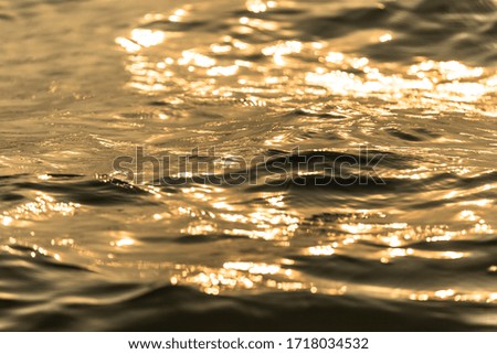 Water surface with moving wave of golden water reflecting 
with sunlight background