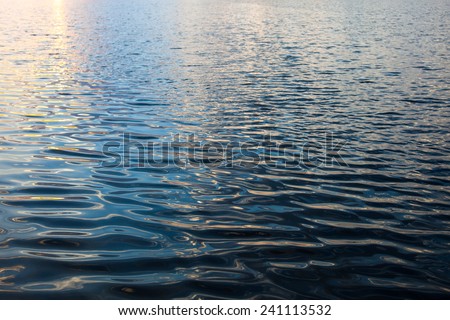 Water surface with ripples and sunrays reflections