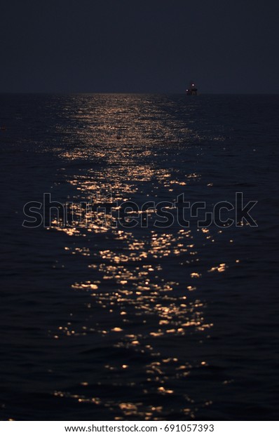 Water surface of sea at night with moon\
reflections in darkness