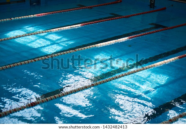 Water surface in the\
sports swimming pool. Blue water and swim lane dividers. Sports and\
health concept.