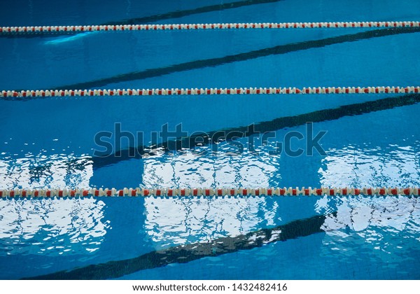 Water surface in the\
sports swimming pool. Blue water and swim lane dividers. Sports and\
health concept.