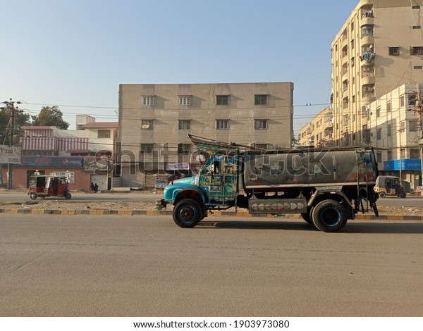 A water tanker is passing in\
front of a apartment building    - Karachi Pakistan - Jan\
2021