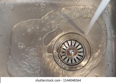 Water from tap running fast to the drain in stainless steel sink. Water supply. save water and plumbing concept