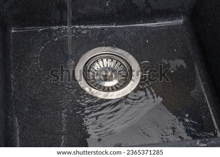 The water in the tap is turned on and flows into the drain hole
