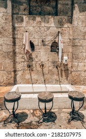 Water Taps And Wooden Seats Used For Islamic Ritual Washing Or Ablution In Mosque. Vintage Empty Chairs And Bronze Water Faucets For Ablution Body Purification Ceremony. Islam Religion Concept