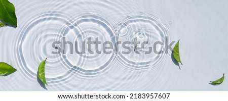 Water texture, clear water surface with rings and ripples and green leaves
