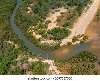 The Water Of A Tidal Creek Winding Through Coastal Vegetation From The Sandy Beach And The Ocean