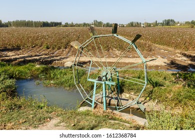 Water Turbine On A Cotton Field. Water Wheel And Channel For Watering Plants On The Field.