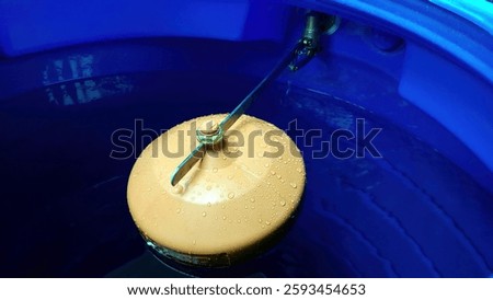 The water valve float gently rests on the surface of the clear water, adjusting the water level in a serene blue storage tank, surrounded by calm reflections.