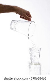 Water, vigorously poured from a jug overflowing splashing from a glass, on a white background