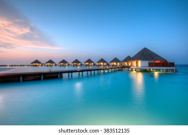 Water Villas On Maldives Resort Island In Sunset