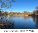 water with wood mooring on beautiful tranquil lake environment with tree plant and bush reflections, blue sky on peaceful Spring morning light 