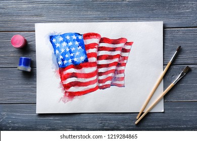 Watercolor painting of American national flag with brushes on wooden table