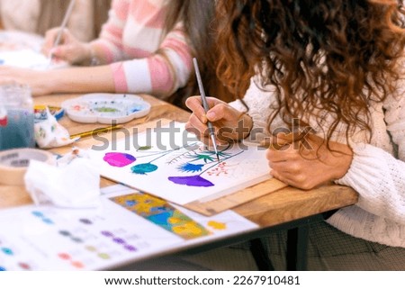 Watercolor Painting Workshop. Young woman drawing with watercolors at table indoors, closeup