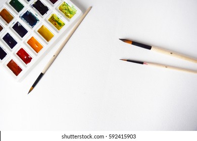 Watercolor paints and brushes, top view. Creative artistic mockup with copyspace.