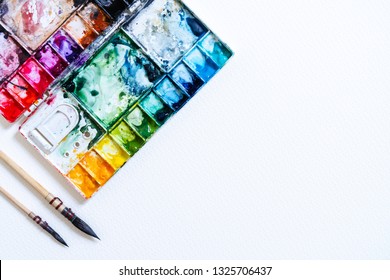 Watercolor in palette with blobs of paint and a brush. Vintage stylized photo with white texture. Copy space for add text or art work designs. - Powered by Shutterstock