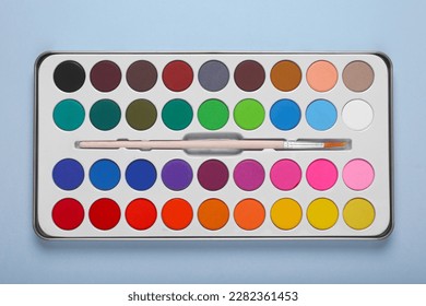 Watercolor palette with brush on light blue background, top view - Powered by Shutterstock