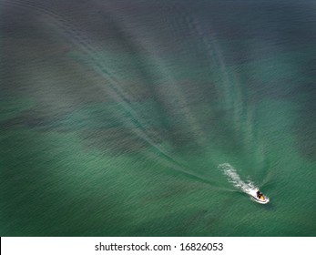Watercraft making waves on a blue-green lake.