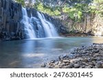 The waterfall is a 10 m high waterfall that cascades over basal steles into a pool. Tropical nature and landscape at Rochester Falls, Mauritius.