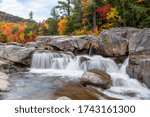 Waterfall along a mountain river on a cloudy autumn morning. Stunning autumn colours in background.